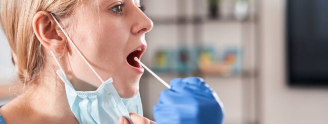 Side view of a blonde female patient receiving a cotton swab test orally.