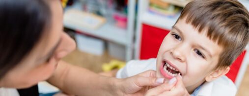 A young child sitting in a dentist's office with a dentist examining his teeth.