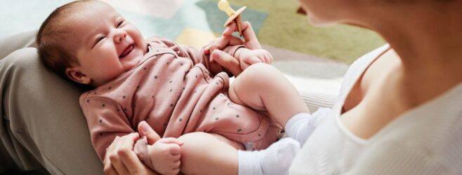 A smiling baby looks up at their mom or caregiver.