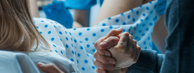 A woman holds her partner's hand while in labor.