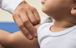 A medical professional examines a child's arm at the shoulder while diagnosing Erb's palsy.